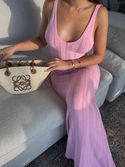 Woman in a pink dress holding a woven bag on a boat