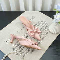 Pink high-heeled shoes with bow details on a surface with text and flowers.
