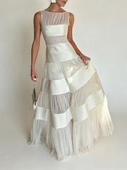 O-neck sleeveless maxi dress with mesh and satin panels and hand holding purse
