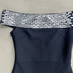 Black dress with a decorative silver waistband on a beige background