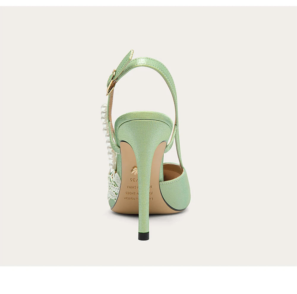 Mint green high-heeled shoe with studded details on a light gray background