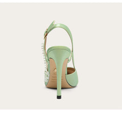 Mint green high-heeled shoe with studded details on a light gray background
