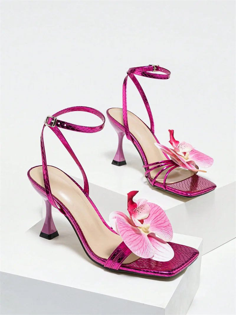 Pink high-heeled sandals with floral decorations on a white background