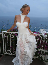 Woman in a white lace dress standing on a balcony with ocean view