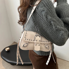 Person wearing a beige studded handbag with a neutral background