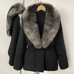 Black coat with large fur collar on a hanger against a white background