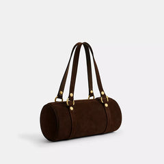 Brown leather handbag with gold hardware on a light gray background