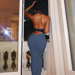 Woman in a blue dress standing in front of a mirror with a cityscape view.