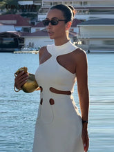 Woman in a white dress with cut-out design by a waterfront