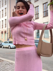 Woman in a pink outfit with a beige bag on a city street