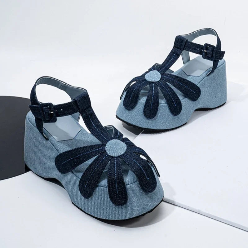 Close-up of denim wedge platform sandals showcasing the flower embellishment and buckle strap.