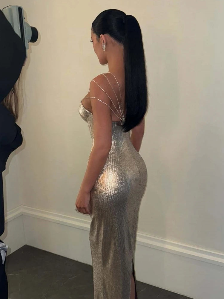Woman wearing a silver sequin dress standing against a plain wall.