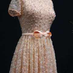 Beige dress with floral embellishments and a pink bow on a black background