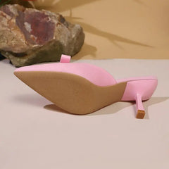 Pink high-heeled shoe with a textured sole on a neutral background