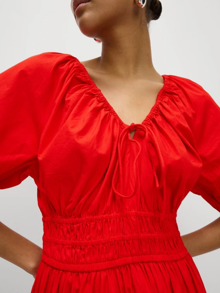 Red dress with puff sleeves worn by a person on a plain background-close-up