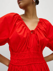 Red dress with puff sleeves worn by a person on a plain background-close-up