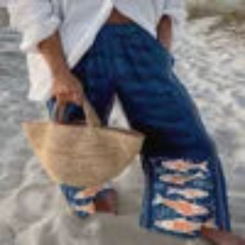 Person wearing ripped jeans and a straw hat on a beach