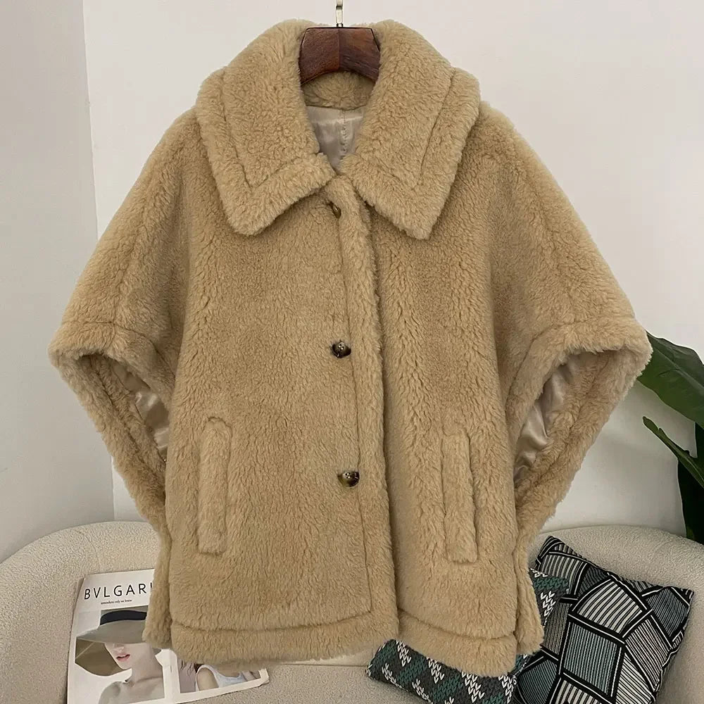 Beige fleece jacket on a hanger against a white wall with a magazine and decorative pillows below.