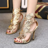 Gold metal wing stiletto heels worn on feet
