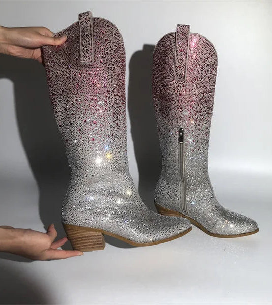 Silver glittery boots being held against a white background