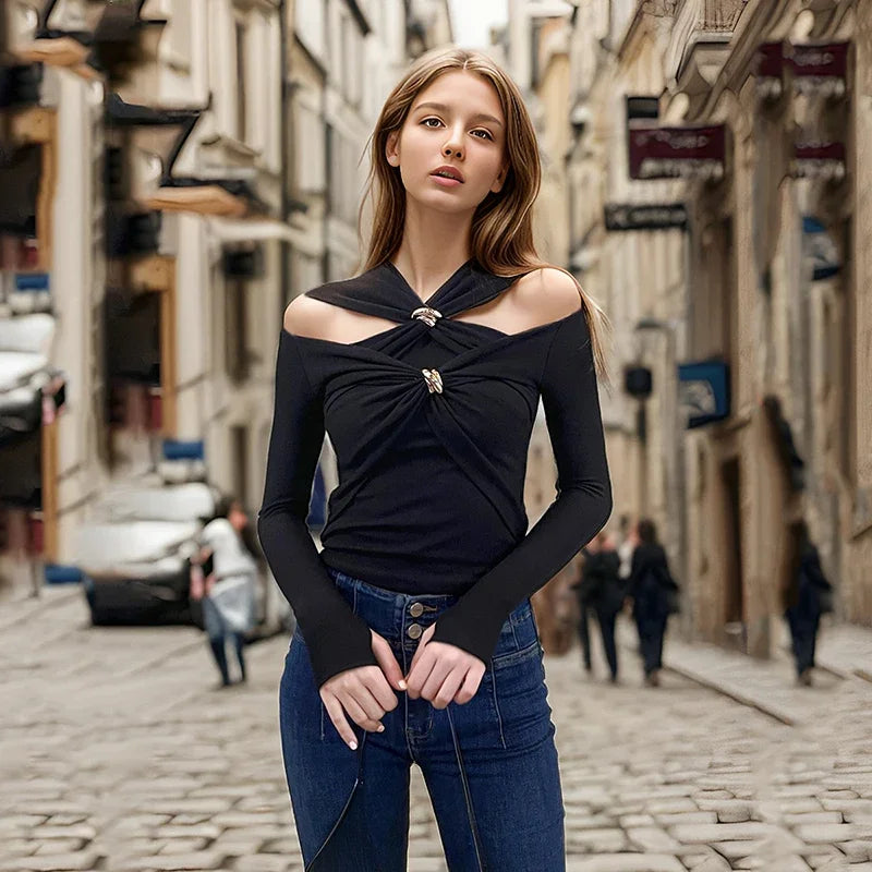 Woman in a black top and blue jeans standing on a city street.