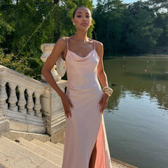Woman in a pink dress standing by a lake with trees in the background