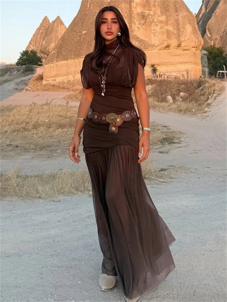 Woman in a brown dress standing in front of rock formations