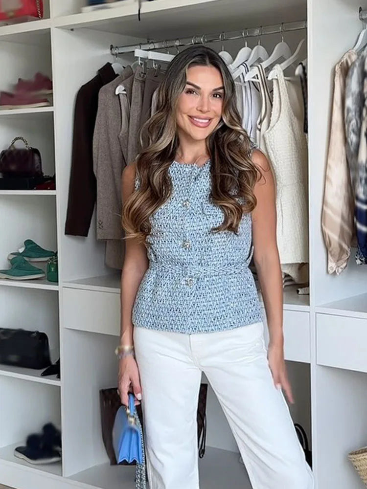Woman standing in a well-organized closet wearing a blue top and white pants.