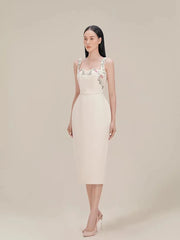 Woman wearing a light-colored dress with floral embellishments on a plain background