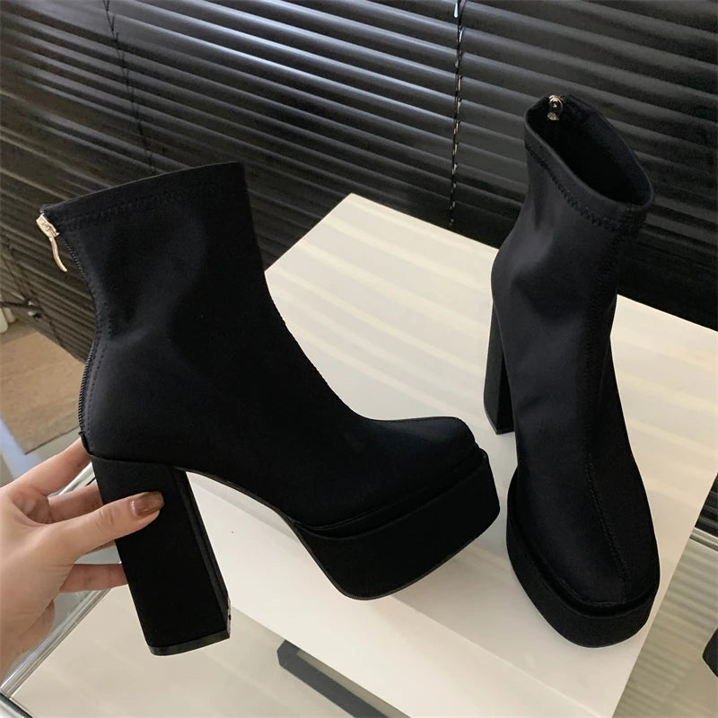 Black platform ankle boots on a white surface with a blurred background