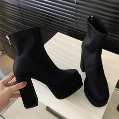 Black platform ankle boots on a white surface with a blurred background