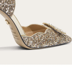 Gold glitter high-heeled shoes on a light gray background