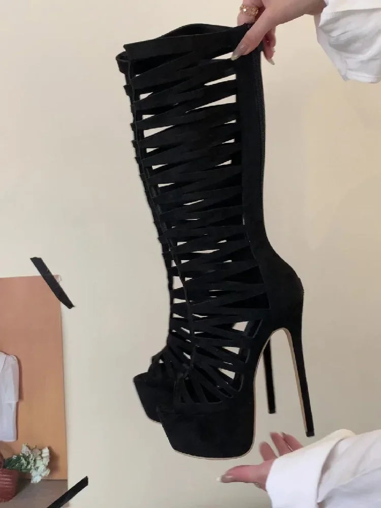 Black high-heeled boot with criss-cross design held by a person against a neutral background