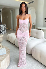 Woman in a pink lace dress sitting on a white couch in a modern living room.