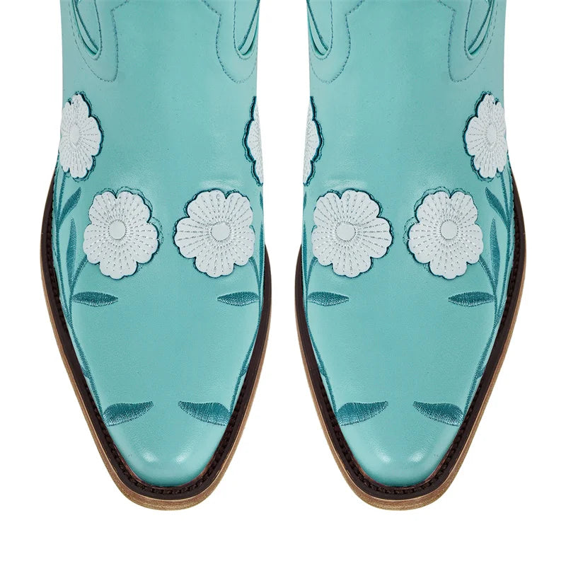 Turquoise cowboy boots with white floral patterns on a white background