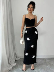 Woman wearing a black outfit with white floral details against a neutral background