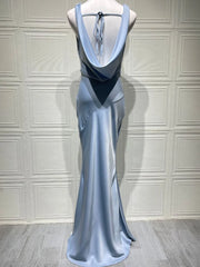 Blue evening gown on a mannequin against a white paneled wall.