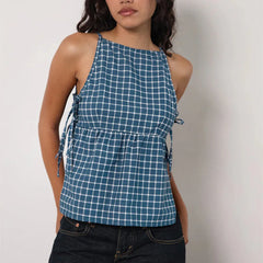 Woman wearing a blue checkered halter top against a plain background