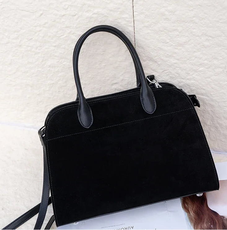 Black handbag on a textured white surface