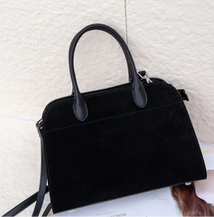 Black handbag on a textured white surface
