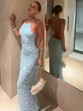 Woman in a light blue sequin dress standing in front of a mirror.