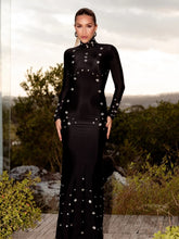 Woman wearing a black dress with silver embellishments standing outdoors.
