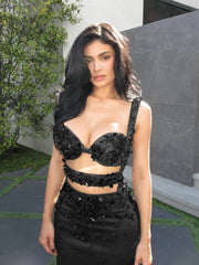 Woman wearing a black beaded outfit standing outdoors.