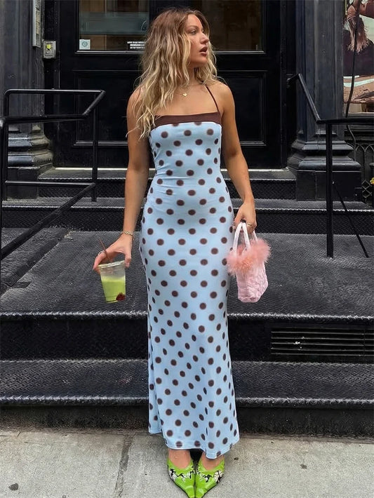 Woman in a polka dot dress standing on a city street.