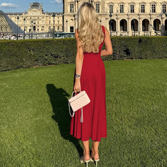 Woman in a red dress standing on grass with a historic building in the background