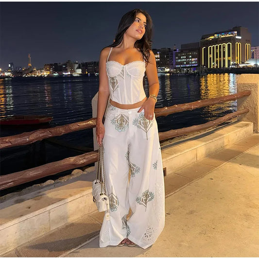 Floral print corset top and wide leg pants set on a model at night by the water.