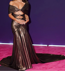 Person wearing a metallic gown on a pink carpet with a purple background