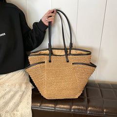 Person holding a woven handbag with black handles against a neutral background