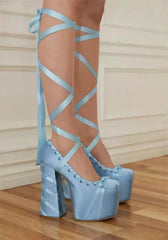 Light blue strappy high-heeled shoes on a wooden floor.