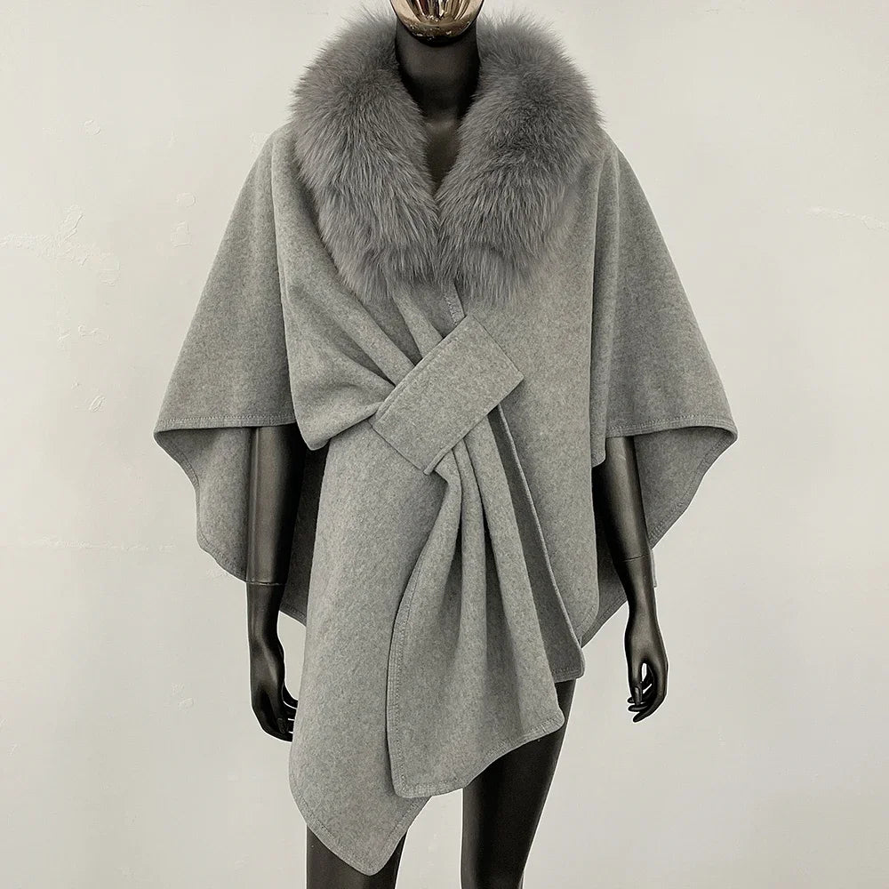 Grey knit poncho with a grey fur collar and knotted front.